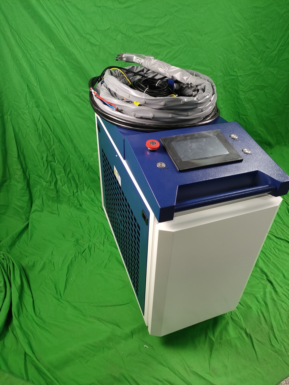 Handheld laser welding machine beside an integrated control cabinet