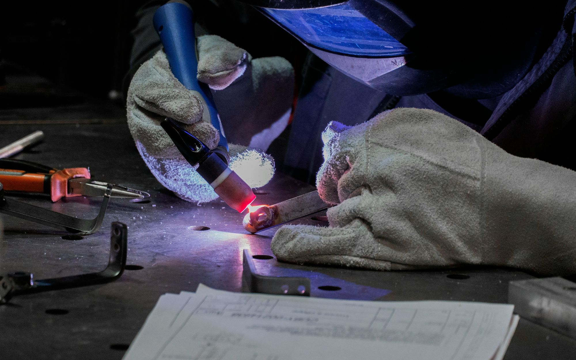 Technician preparing a metal joint beside a process drawing