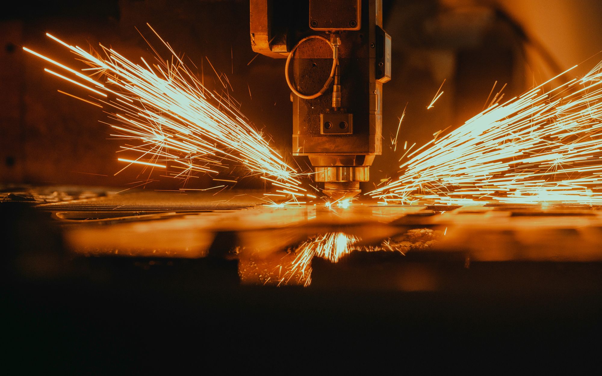 CNC laser cutting machine producing sparks over sheet metal